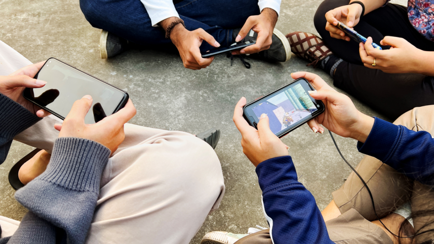 A bunch of young kids playing games on their smartphones.