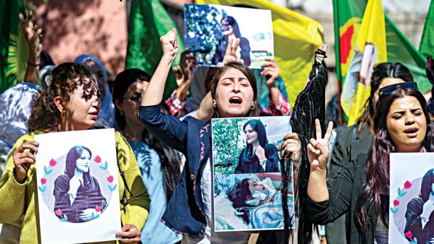 Syrian Kurdish women take part in a demonstration in Syria’s northeastern city of Hasakeh, to express their support for 22-year-old Mahsa Amini (portrait), who died while in the custody of Iranian authorities.