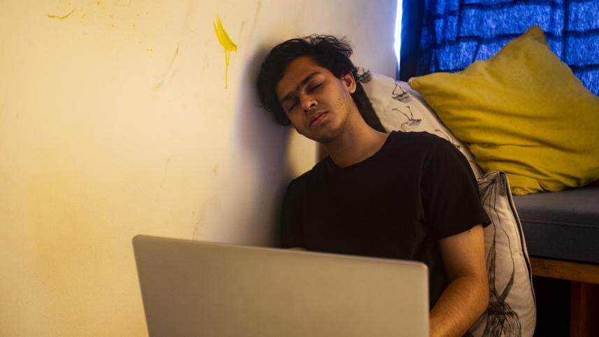 A boy falling asleep while trying to work.