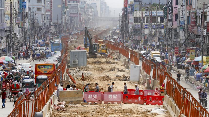 People crossing the street through the construction site of the metro railway.