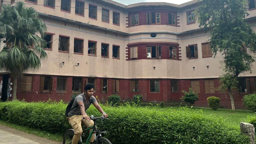 Student cycling past a dormitory hall.