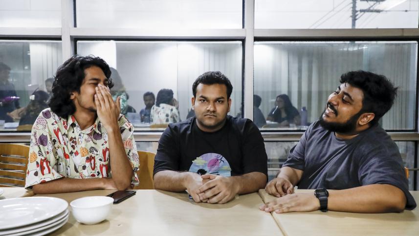 A man with a poker face sitting with two laughing friends.