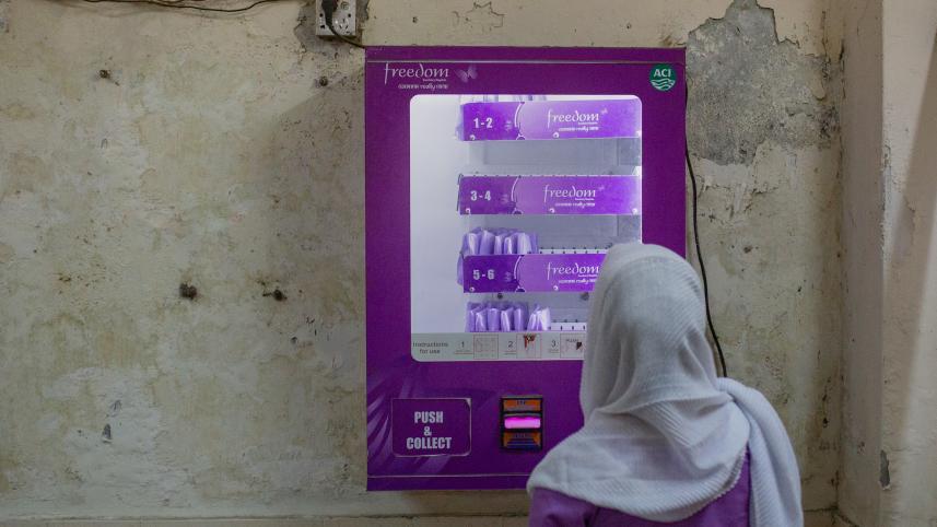 Woman collecting a sanitary pad from a vending machine.
