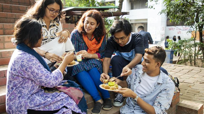 Students huddled together, enjoying a plate of fuchka. 