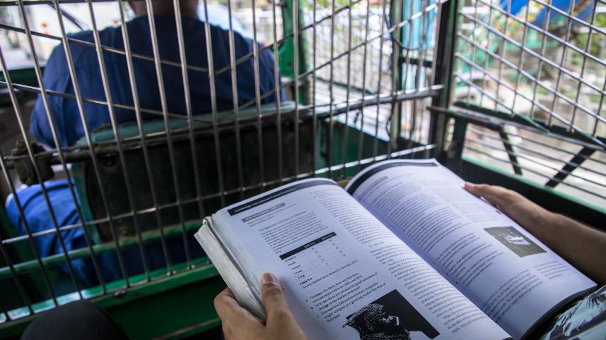 Student reading their textbook inside a CNG. 