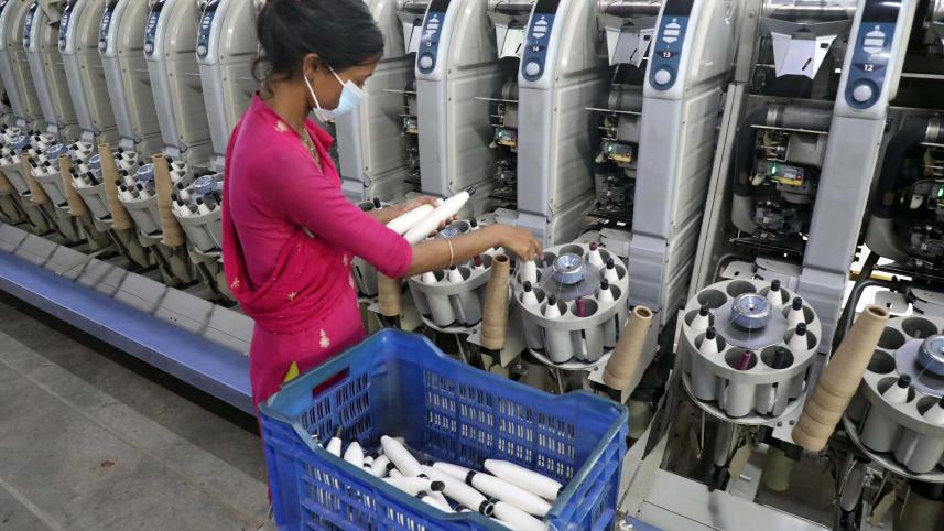 A worker is seen loading thread into a spinning machine at a textile mill in Ashulia of Savar. The picture was taken yesterday.