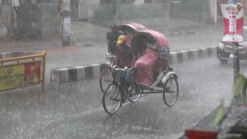 Two rickshaws are crossing Green Road as rain drenches Dhaka