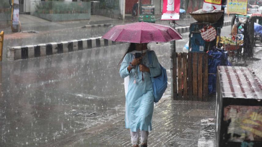 A girl is walking on a footpath amid rain in Dhaka.