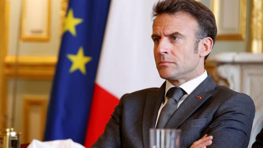 Macron sitting near French flag