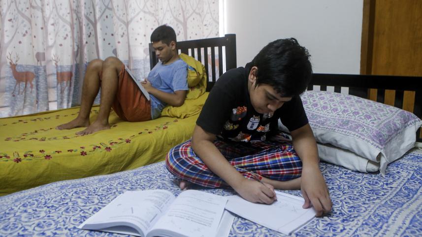 Siblings studying in their separate beds.  