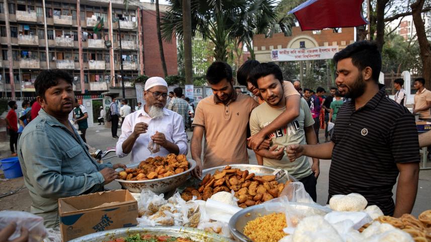 A group of people huddled around a stall that is selling iftar. 
