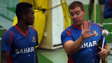 Bangladesh cricketer Al-Amin Hossain (L) listens to bowling coach Heath Streak during an indoor training session