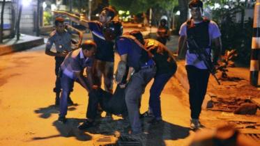 People help an injured person after gunmen attacked the Holey Artisan Café. 