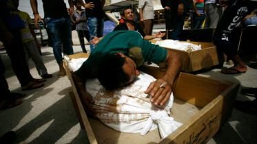 Iraqi men mourn over bodies after they lost five members of their family in a suicide bombing that ripped through Baghdad's busy shopping district of Karrada