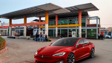 A Tesla going past a fuel pump
