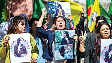 Syrian Kurdish women take part in a demonstration in Syria’s northeastern city of Hasakeh, to express their support for 22-year-old Mahsa Amini (portrait), who died while in the custody of Iranian authorities.