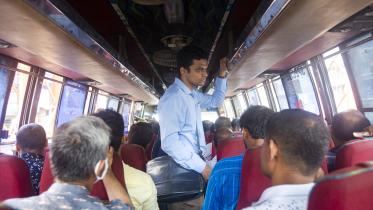 An exhausted person standing in the aisle of a bus. 