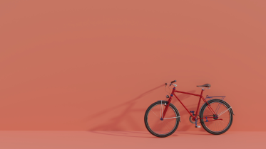 A red bicycle against a solid orange backdrop.  
