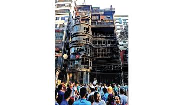 onlookers gather in front of the charred seven-storey building.