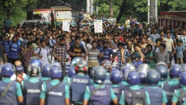 An army of police standing in the way of students protesting.   