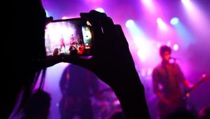 Fan taking photo of performers in a concert