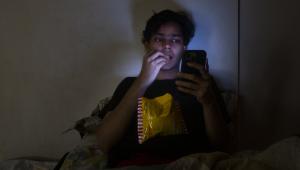 A person eating chips and using their phone